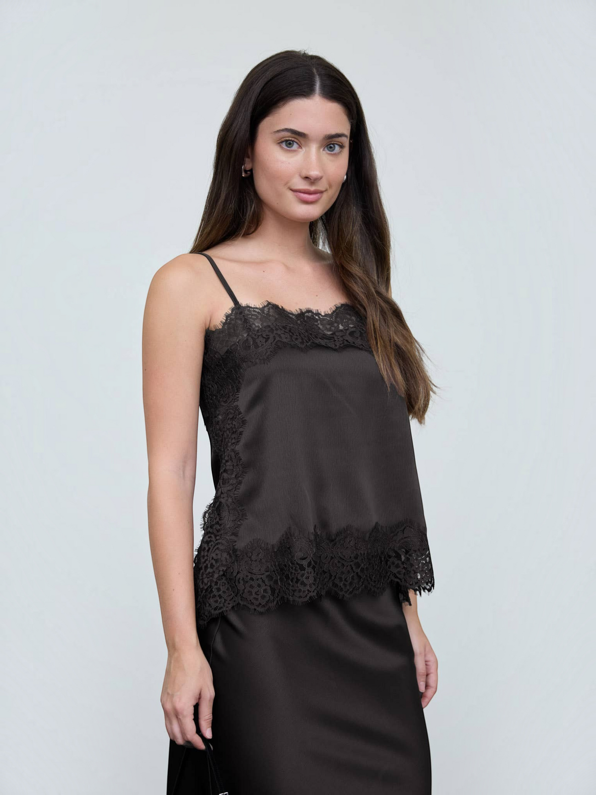 Woman wearing a black lace-trimmed top against a plain background