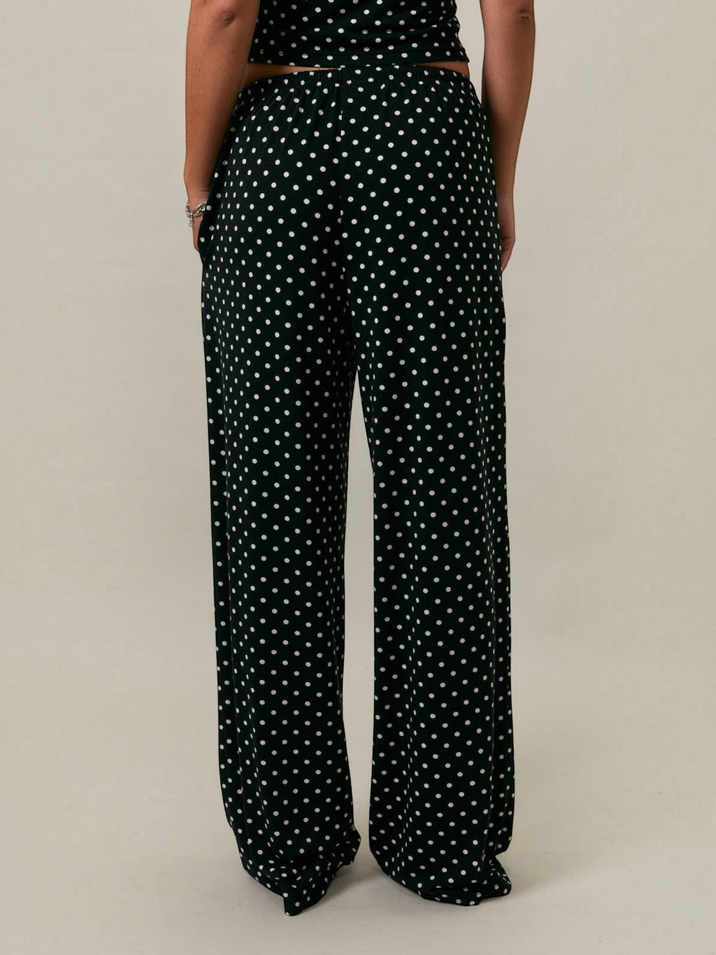 Mialur Boutique Luna Polka Dot Pants shown from the back, featuring a black and white all-over polka dot print, relaxed wide-leg silhouette, full-length drape, and elastic waistband