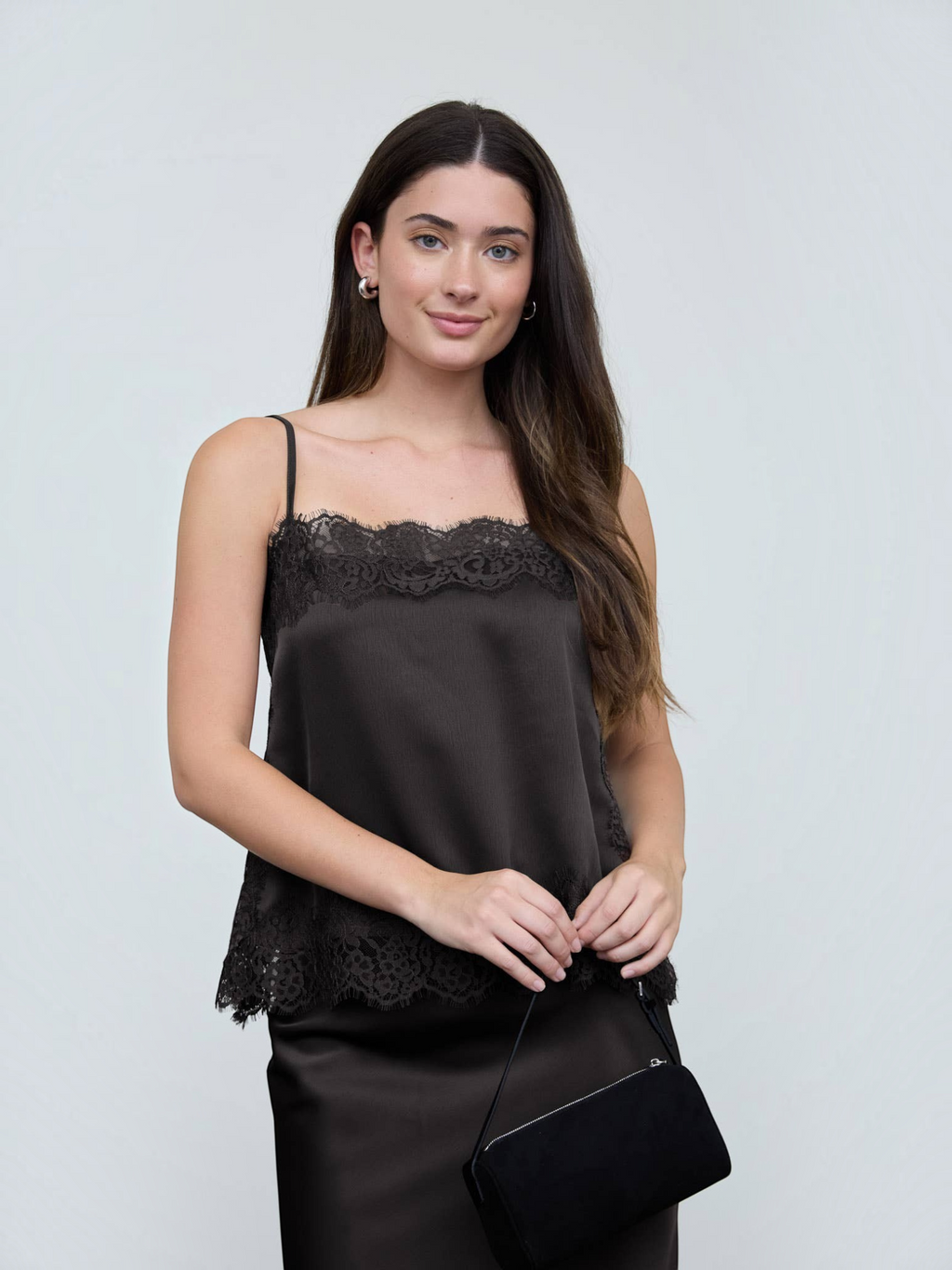 Woman wearing a black lace-trimmed top against a plain background