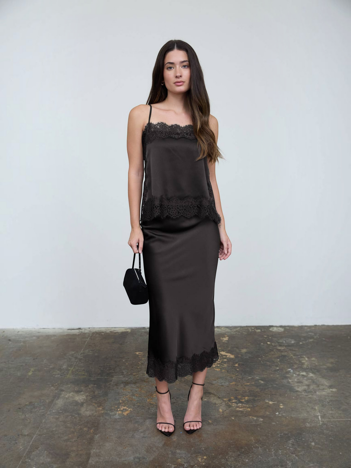 Model wearing Mialur black satin midi skirt and matching camisole with delicate lace trim and high-waisted silhouette