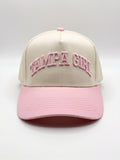 Mialur Boutique - A structured baseball cap with a cream-colored crown and a light pink brim, featuring 'TAMPA GIRL' embroidered in pink arched lettering on the front. The cap is photographed against a neutral light gray studio background.