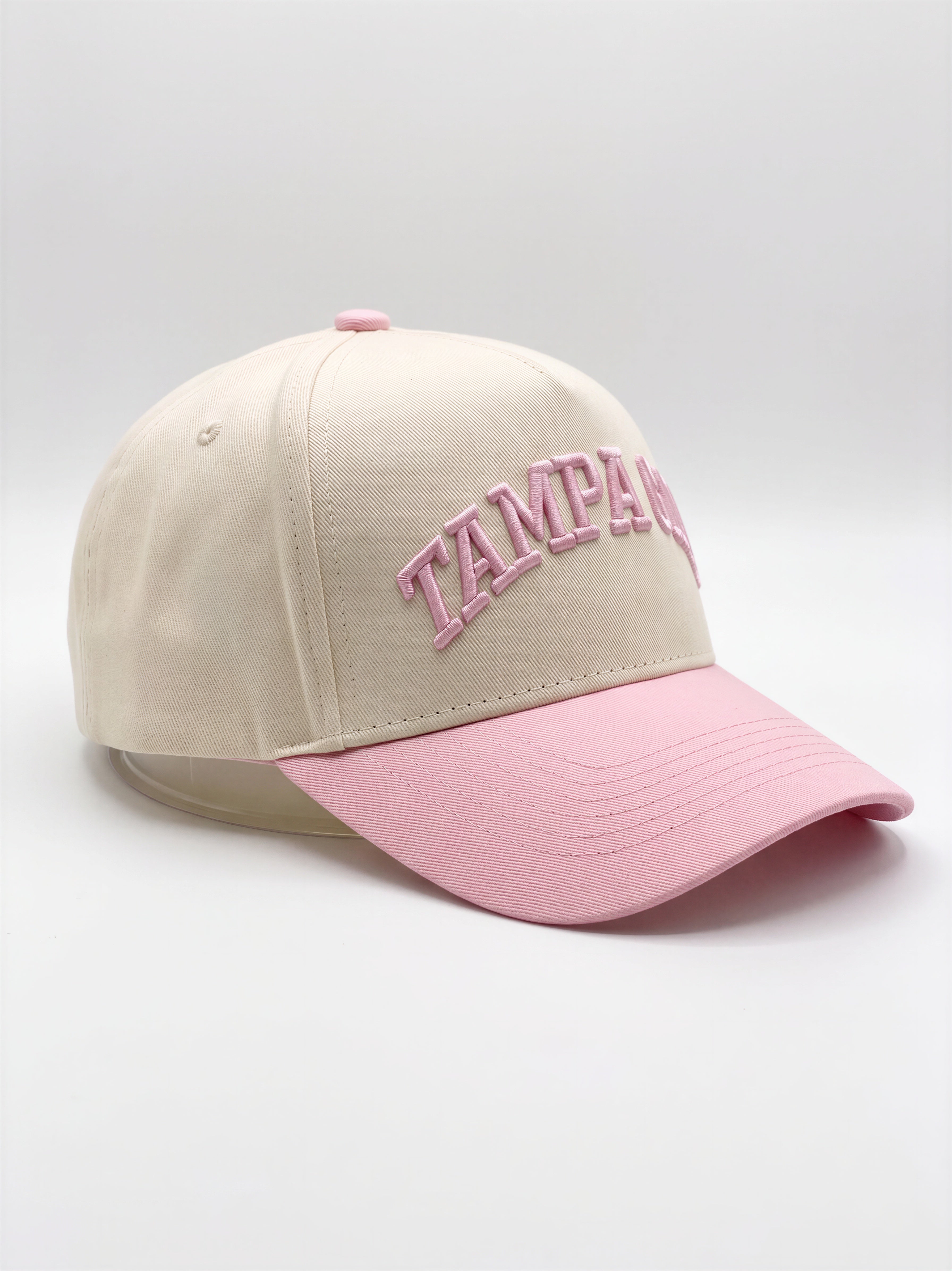 Mialur Boutique - A baseball cap with a cream-colored crown and a light pink brim, featuring the word 'TAMPA' embroidered in pink arched lettering on the front.