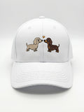 Mialur Boutique - A white baseball cap featuring an embroidered design of two dachshund dogs facing each other with a small heart between them, set against a clean white background.