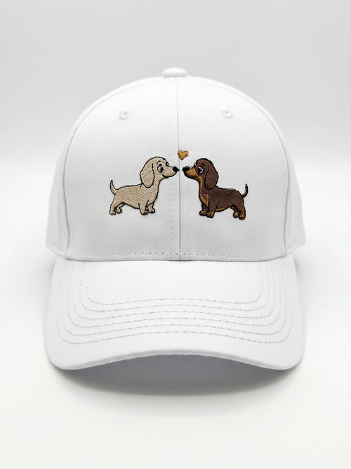 Mialur Boutique - A white baseball cap featuring an embroidered design of two dachshund dogs facing each other with a small heart between them, set against a clean white background.
