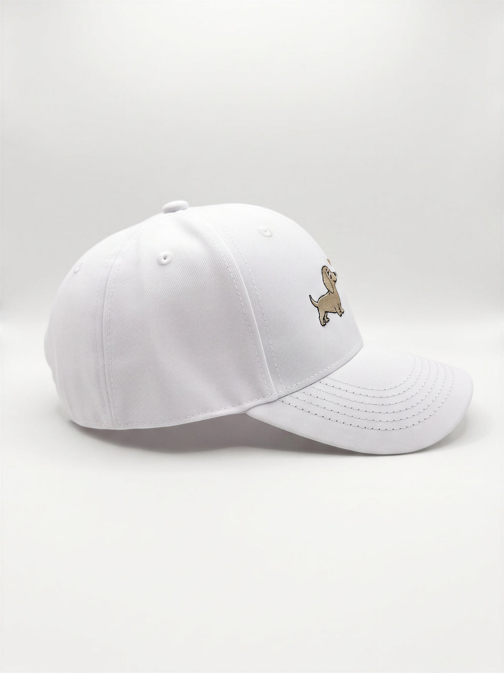 Mialur Boutique - A white baseball cap with a small embroidered dachshund dog logo on the side, photographed against a seamless light gray studio background.