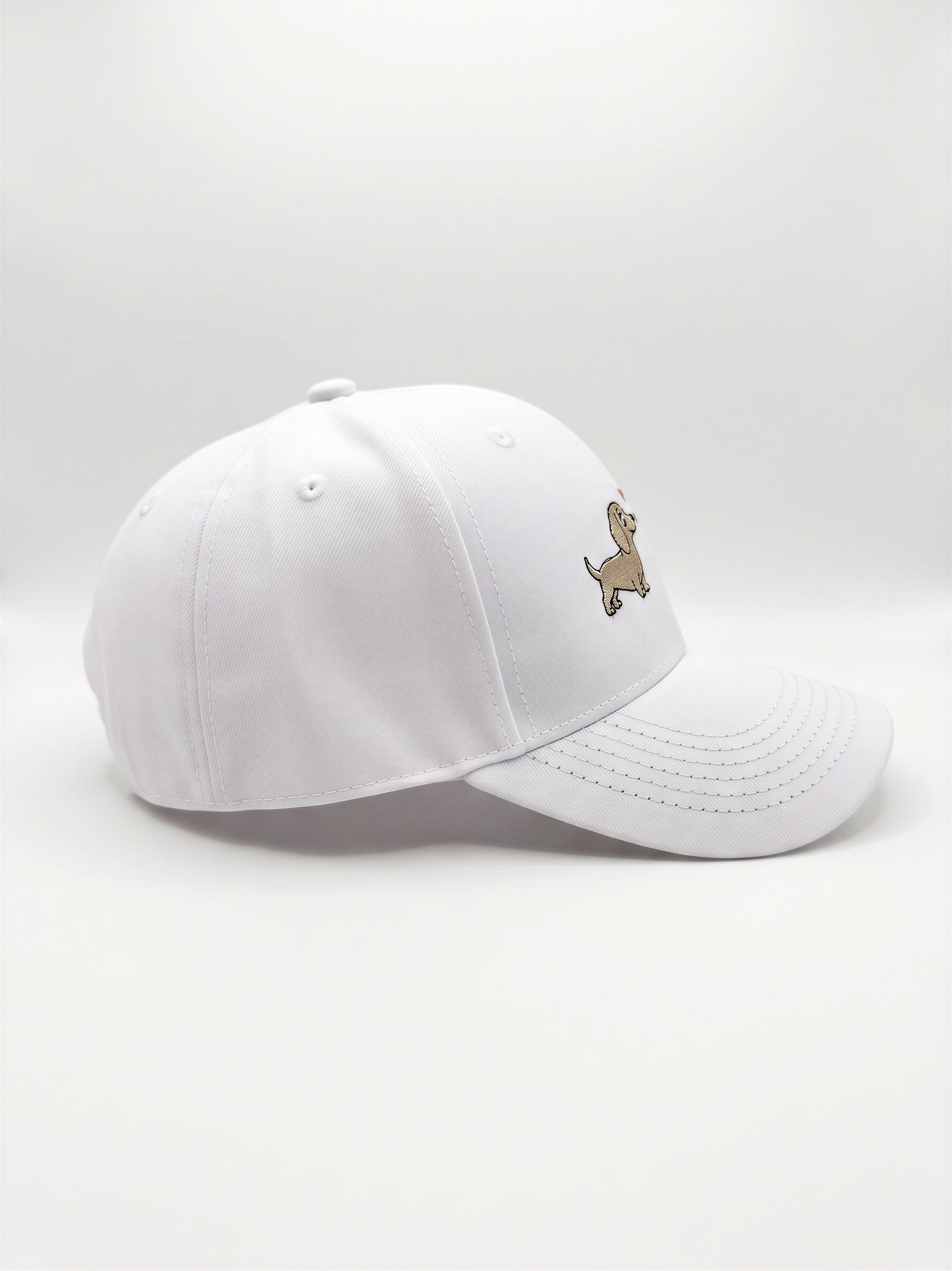 Mialur Boutique - A white baseball cap with a small embroidered dachshund dog logo on the side, photographed against a seamless light gray studio background.