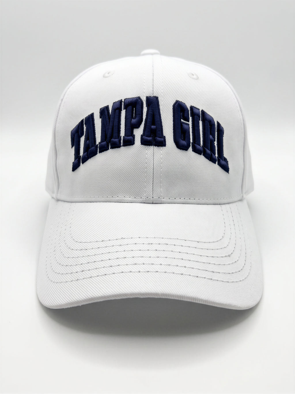 Mialur Boutique - A white baseball cap featuring the words 'TAMPA GIRL' embroidered in navy blue arched block letters across the front, set against a neutral light gray background.