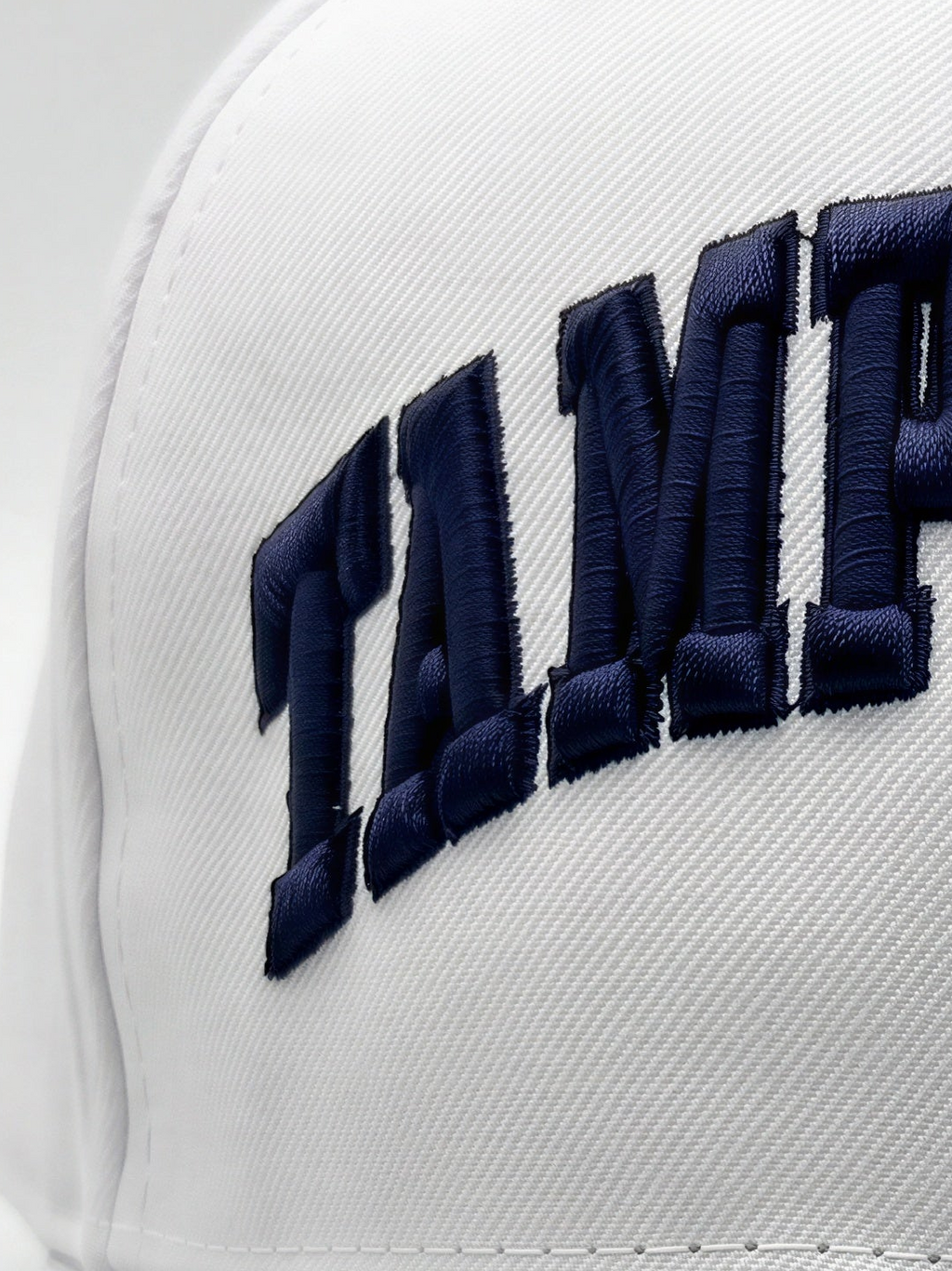 Close-up of a white structured cap with large navy blue embroidered lettering on the front panel.
