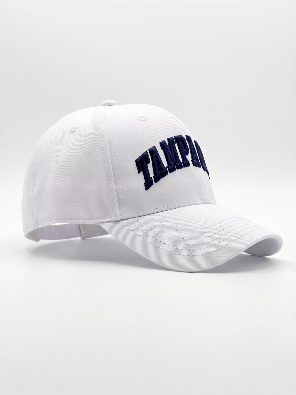 Mialur Boutique - A white baseball cap with 'Tampa' embroidered in navy blue arched lettering on the front, shown against a light gray studio background.