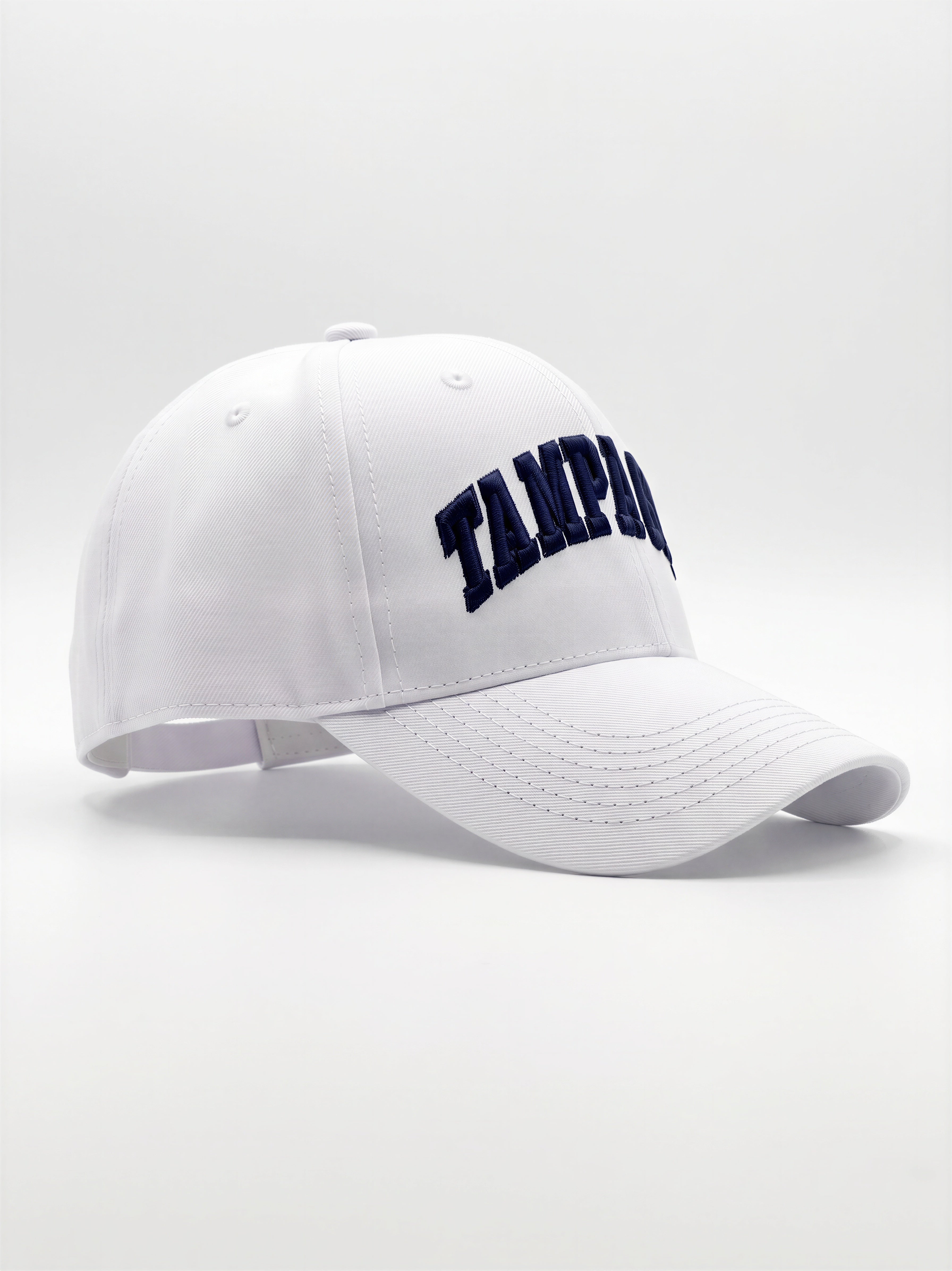 Mialur Boutique - A white baseball cap with 'Tampa' embroidered in navy blue arched lettering on the front, shown against a light gray studio background.