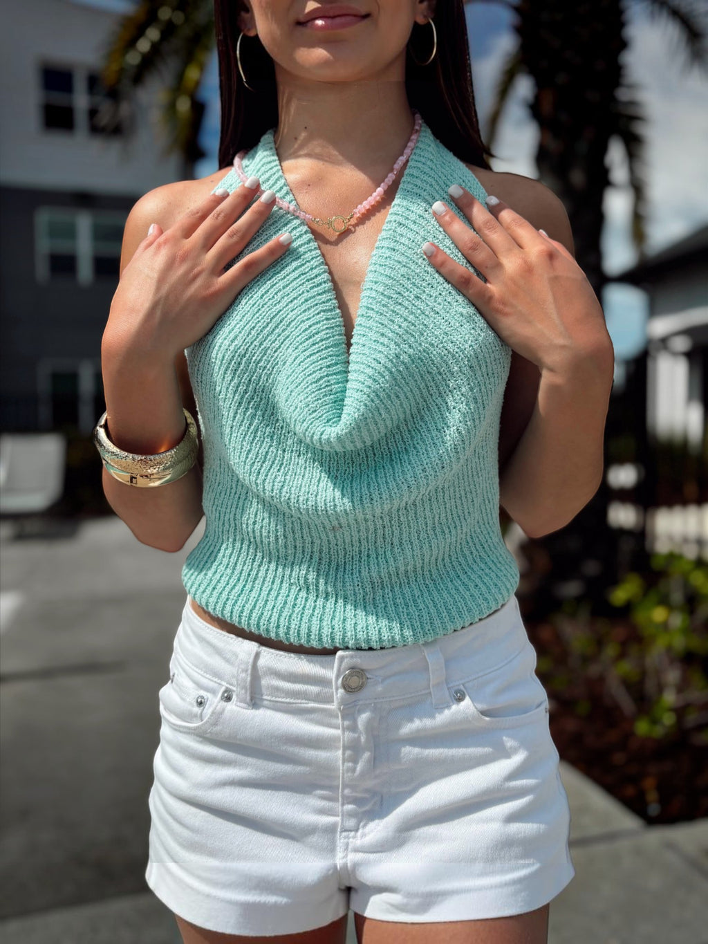 Mialur Boutique - A woman wearing a light mint green ribbed knit halter-style top with a deep V-neck, paired with white denim shorts, standing outdoors.