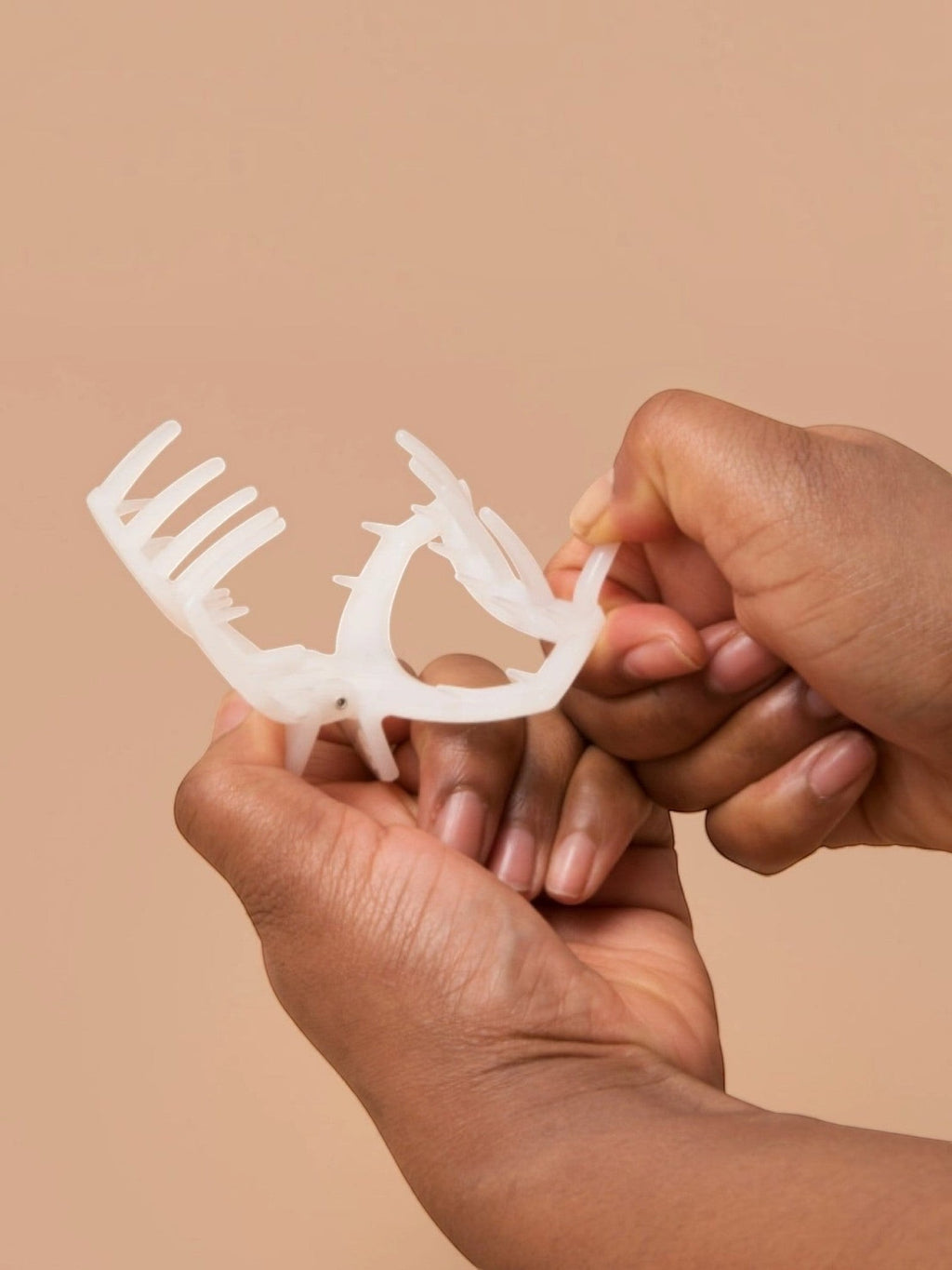 Mialur almond beige medium hair clip with an open claw design and flexible teeth being held by hands