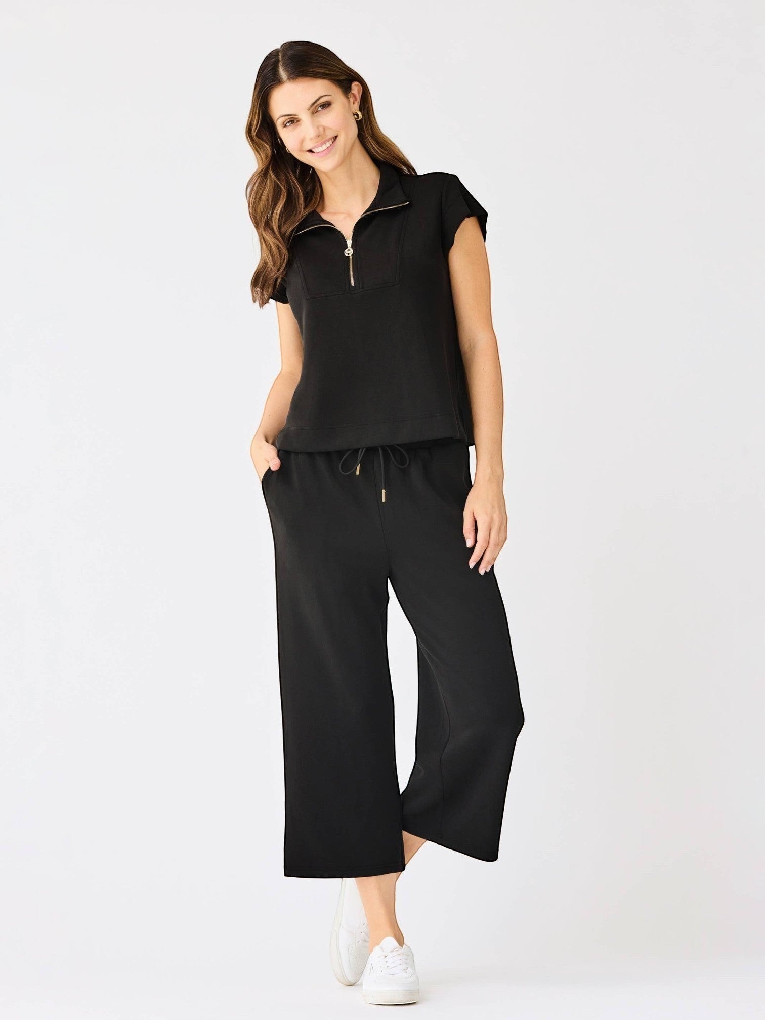 A woman wearing Mialur black cropped wide-leg Avery pants with a drawstring waist and side pockets, styled with sneakers.