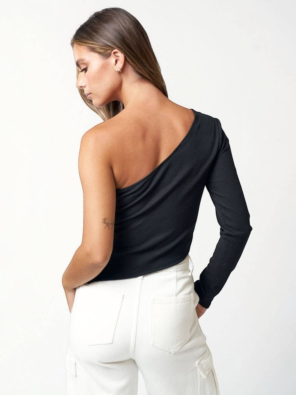 A model wearing a Mialur black ribbed one-shoulder long sleeve top with an asymmetric neckline and side slit detail.