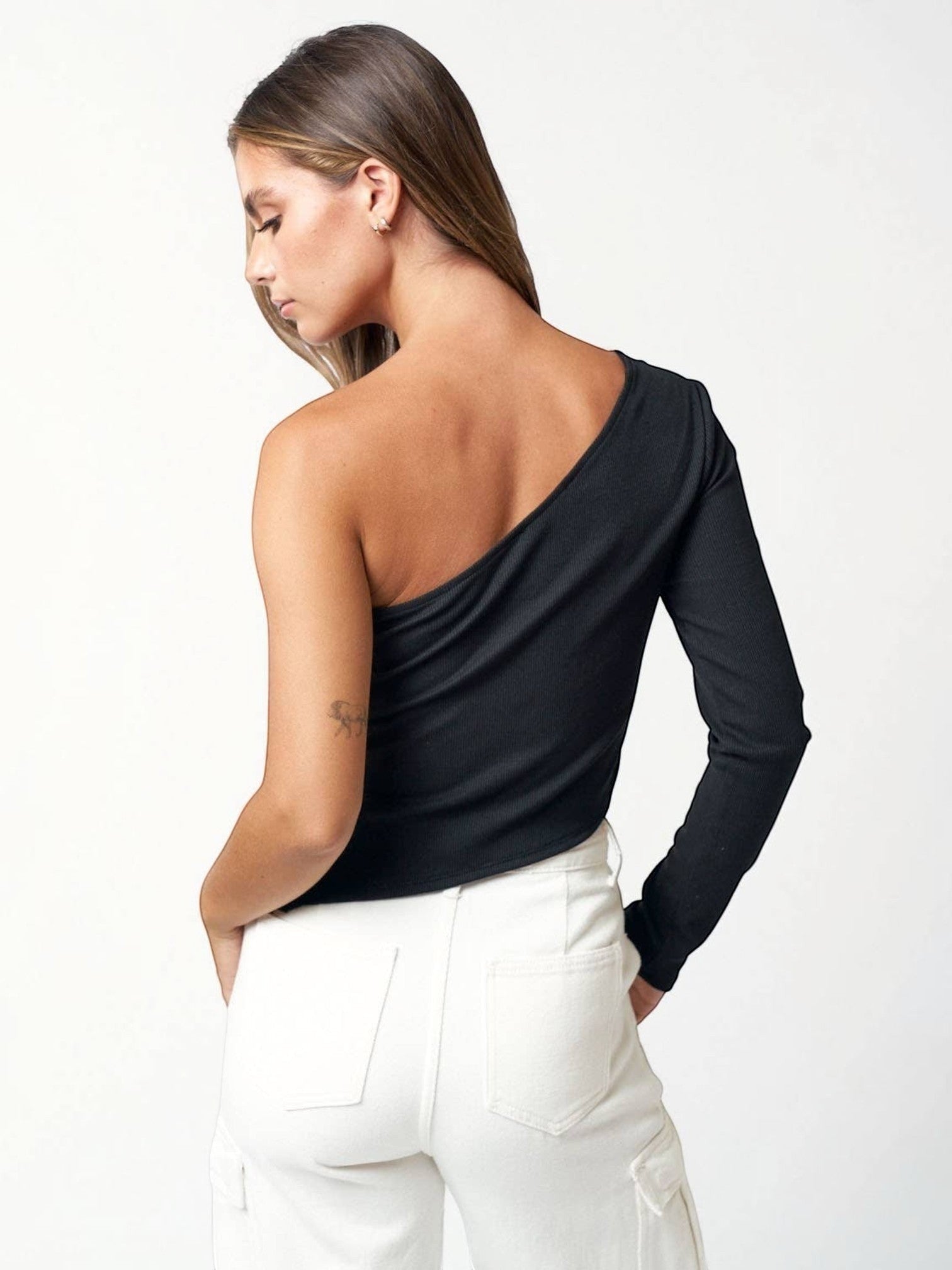 A model wearing a Mialur black ribbed one-shoulder long sleeve top with an asymmetric neckline and side slit detail.