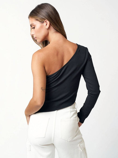 A model wearing a Mialur black ribbed one-shoulder long sleeve top with an asymmetric neckline and side slit detail.