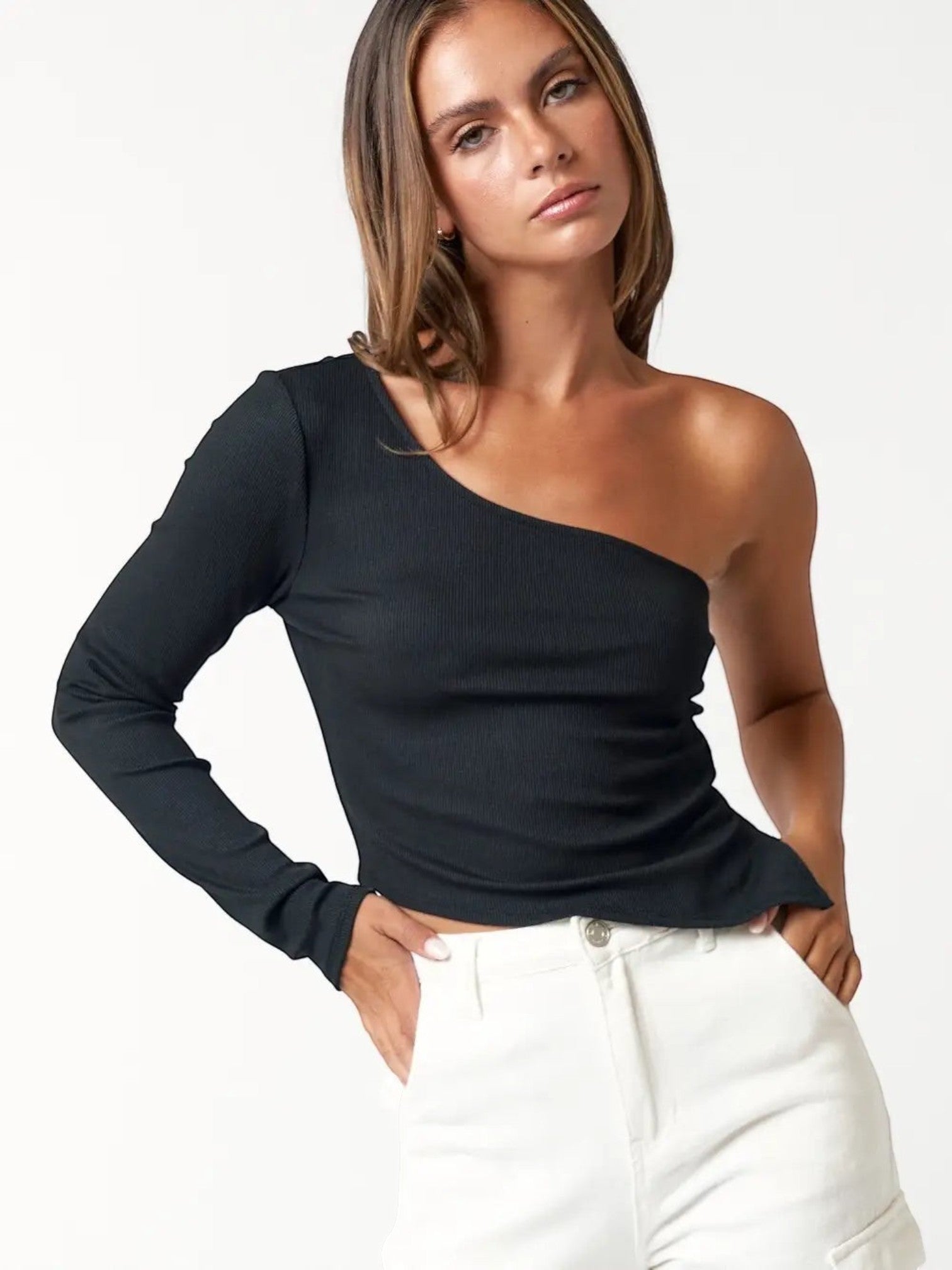 Mialur black ribbed one-shoulder long sleeve top with a fitted silhouette worn by a model with white trousers