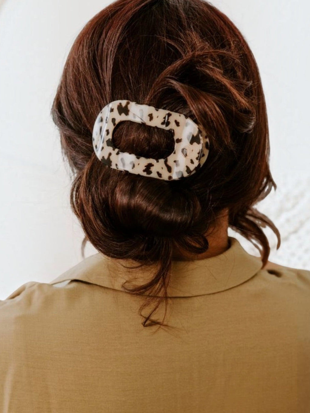 Mialur blonde tortoise medium flat round hair clip worn in a brown bun, featuring a comfortable, durable design.
