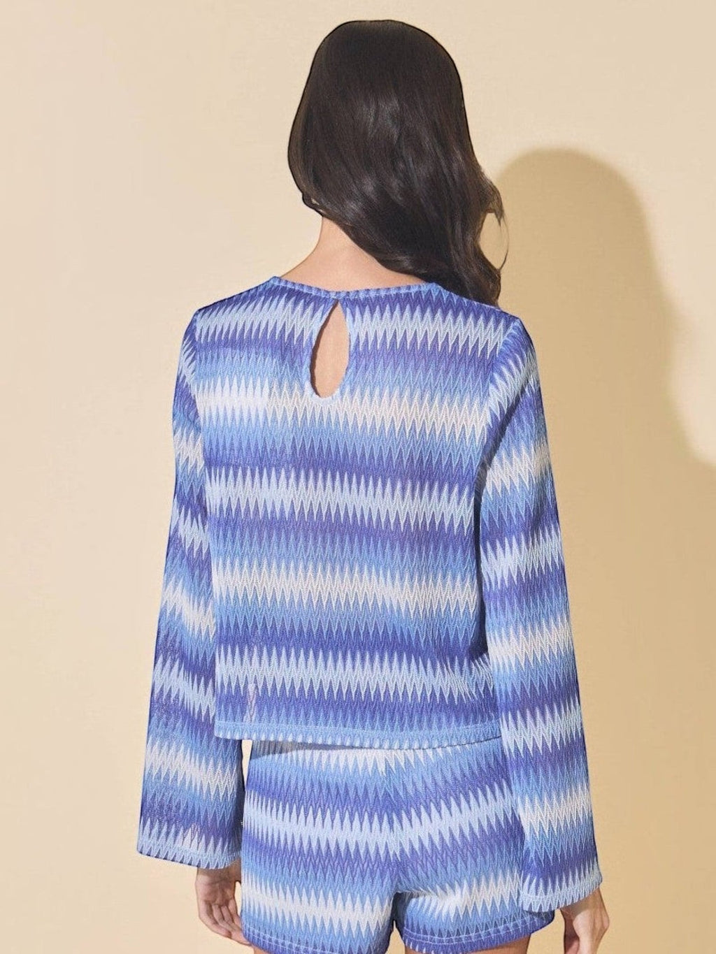 Back view of Mialur blue and white wave-patterned knit sweater with bell sleeves and a keyhole back detail.