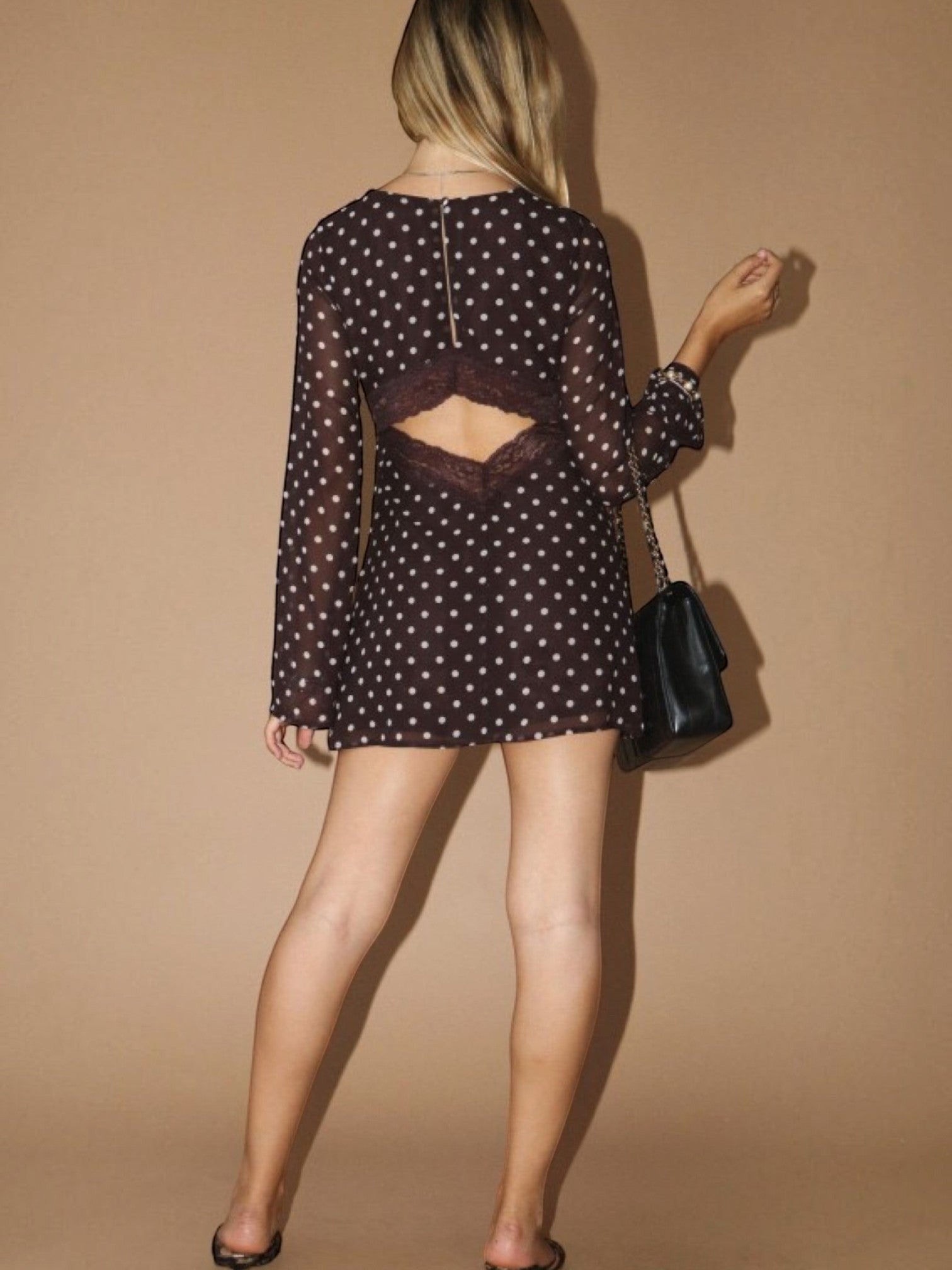 Mialur brown polka dot mini dress with sheer long sleeves, lace trim, and an open-back design worn by a woman.