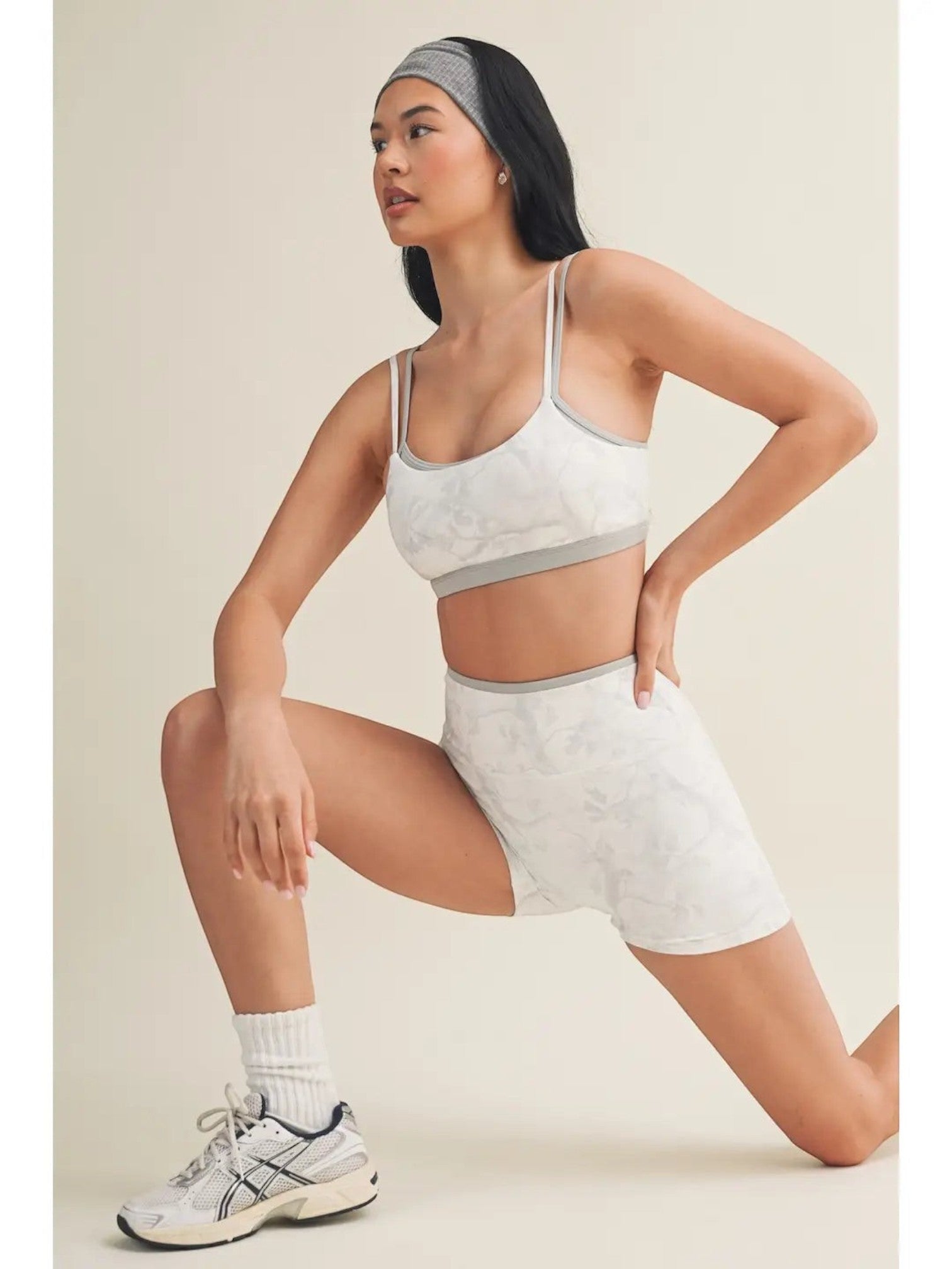 Mialur model wearing a gray and white camo print double layered sports bra and matching shorts in a studio setting.