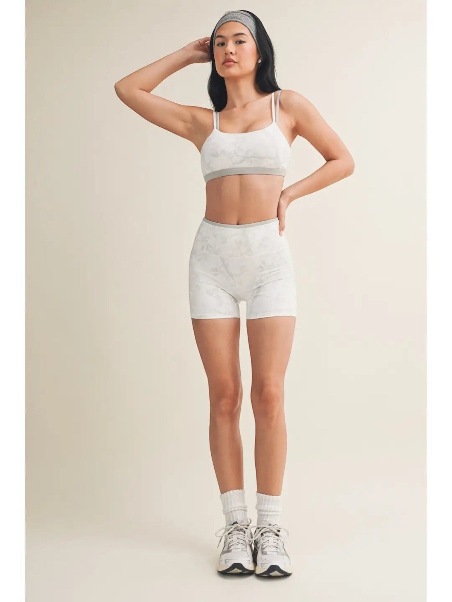 Mialur model wearing a gray and white camo print double-layered sports bra and matching biker shorts with sneakers.