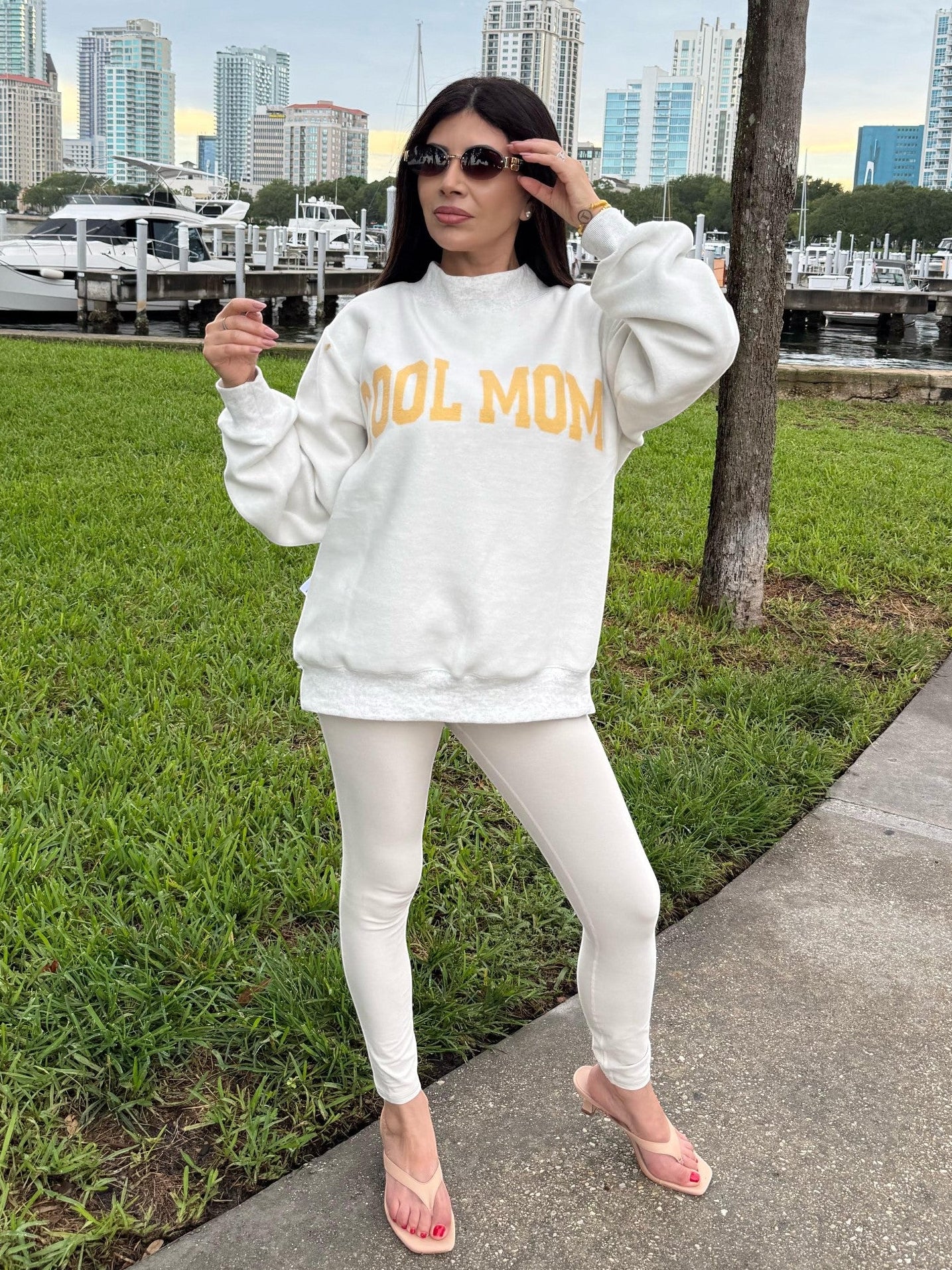 Mialur white reversible mock neck sweatshirt with Cool Mom text in yellow, worn by a woman near a marina.