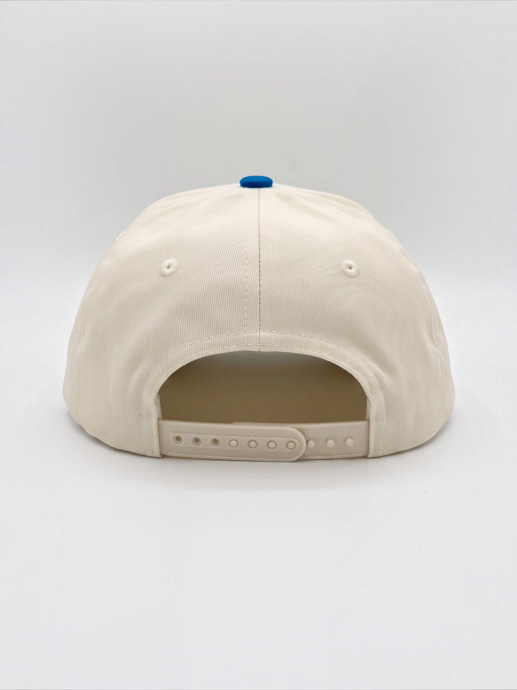 Rear view of the Mialur cream baseball hat with a blue button top and adjustable snapback closure.
