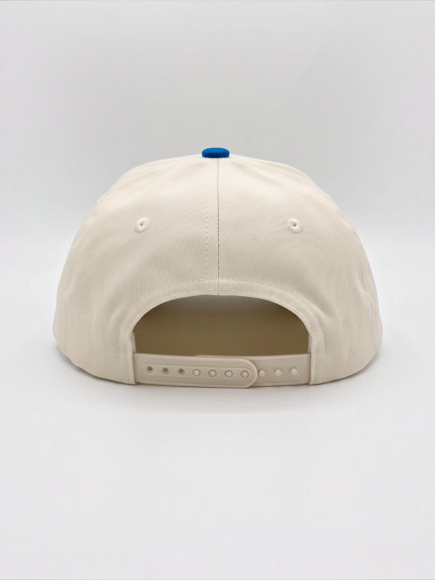 Rear view of the Mialur cream baseball hat with a blue button top and adjustable snapback closure.