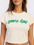 Mialur cream fitted baby tee with green game day script text for football season, worn by a woman.
