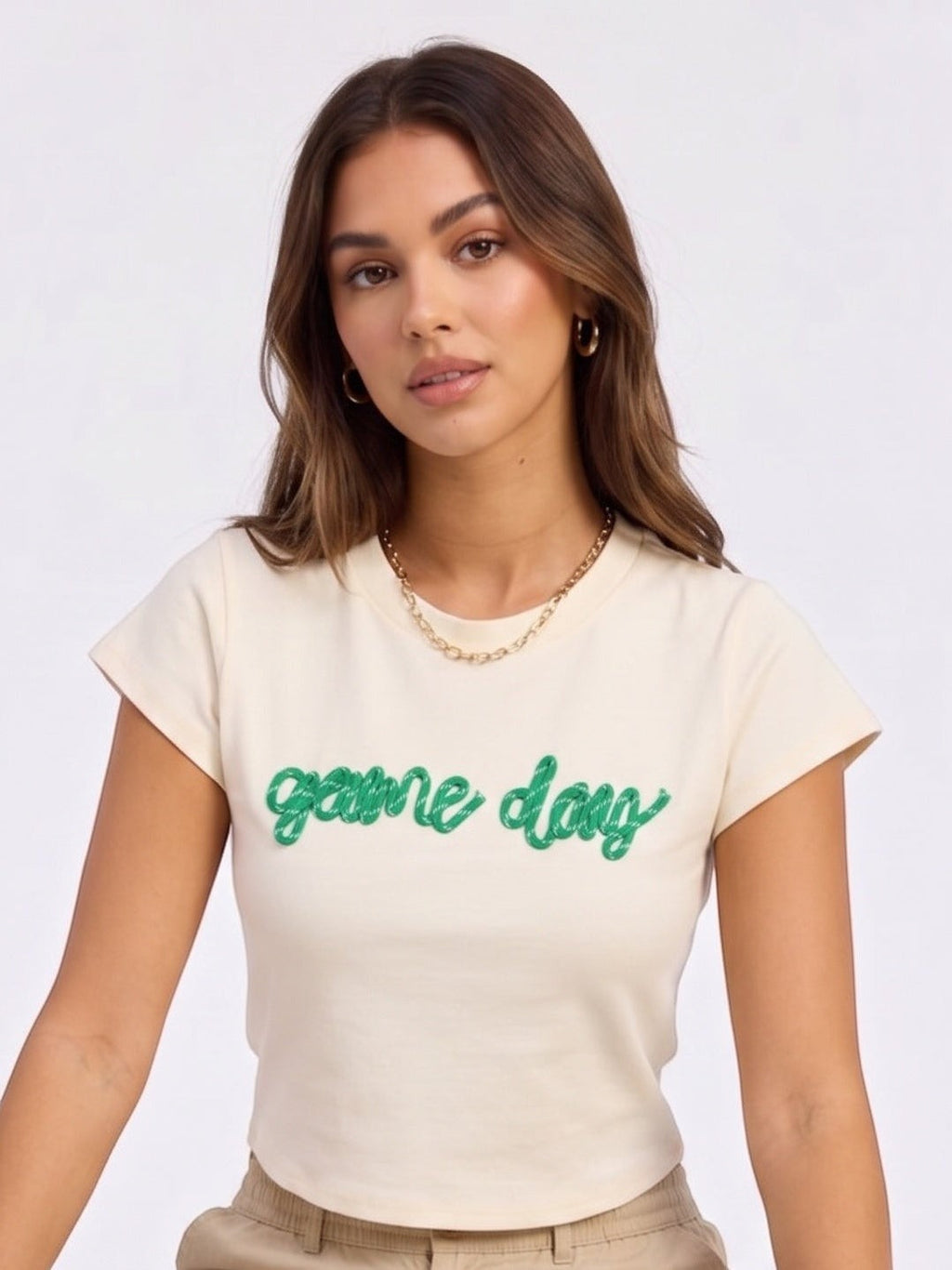 Model wearing a Mialur cream fitted baby tee with green game day script text for football season