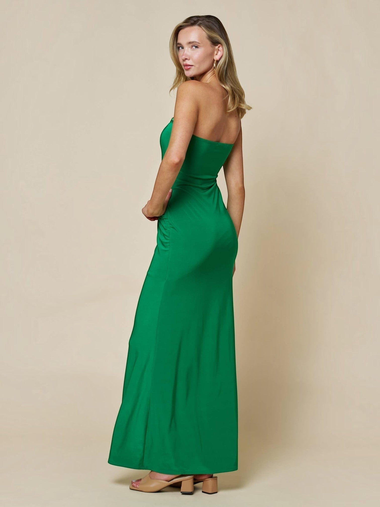 Model wearing Mialur emerald green strapless bodycon maxi dress with gold hardware detail, side view