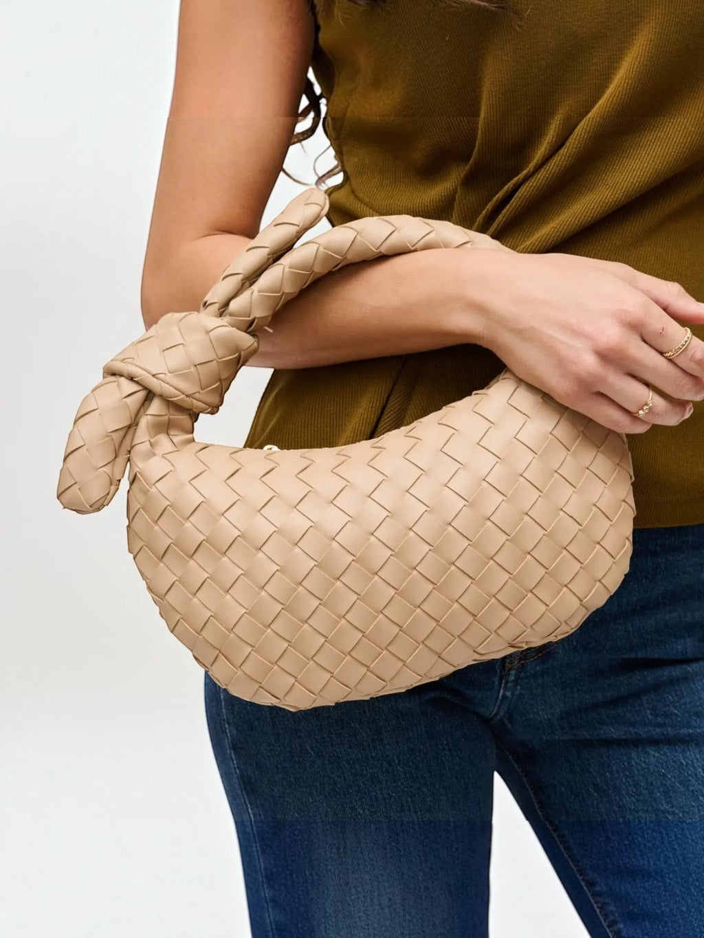 Mialur Emery Clutch in tan vegan leather with a woven texture and signature knot handle held by a woman.