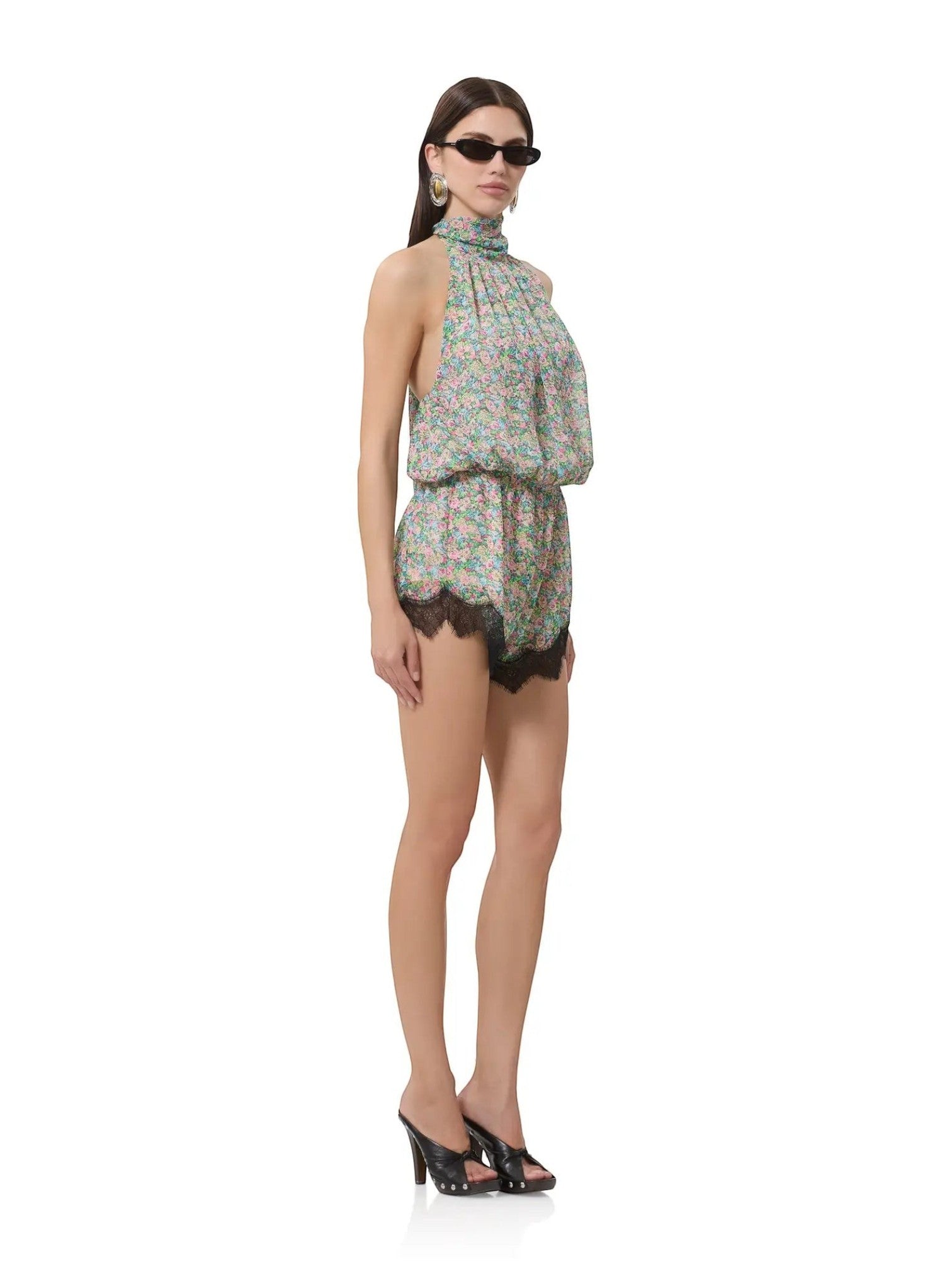 Mialur Fleur floral romper with a high neckline and black lace hem worn by a model in sunglasses and heels