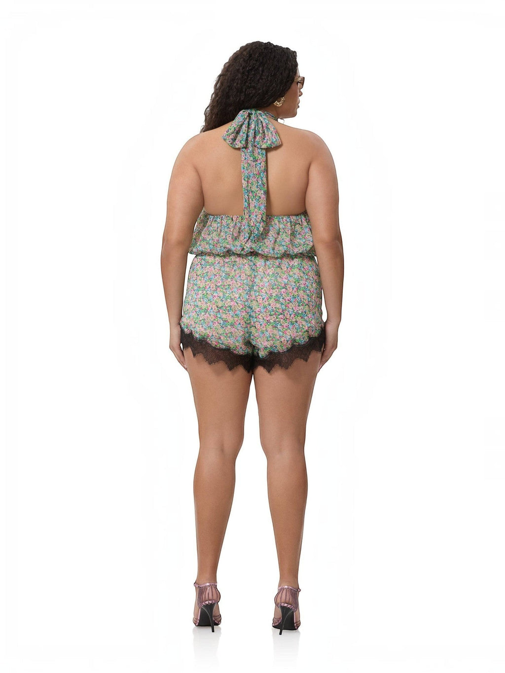 Back view of a model wearing the Mialur Fleur floral romper with a high neckline and black lace trim at the hem.