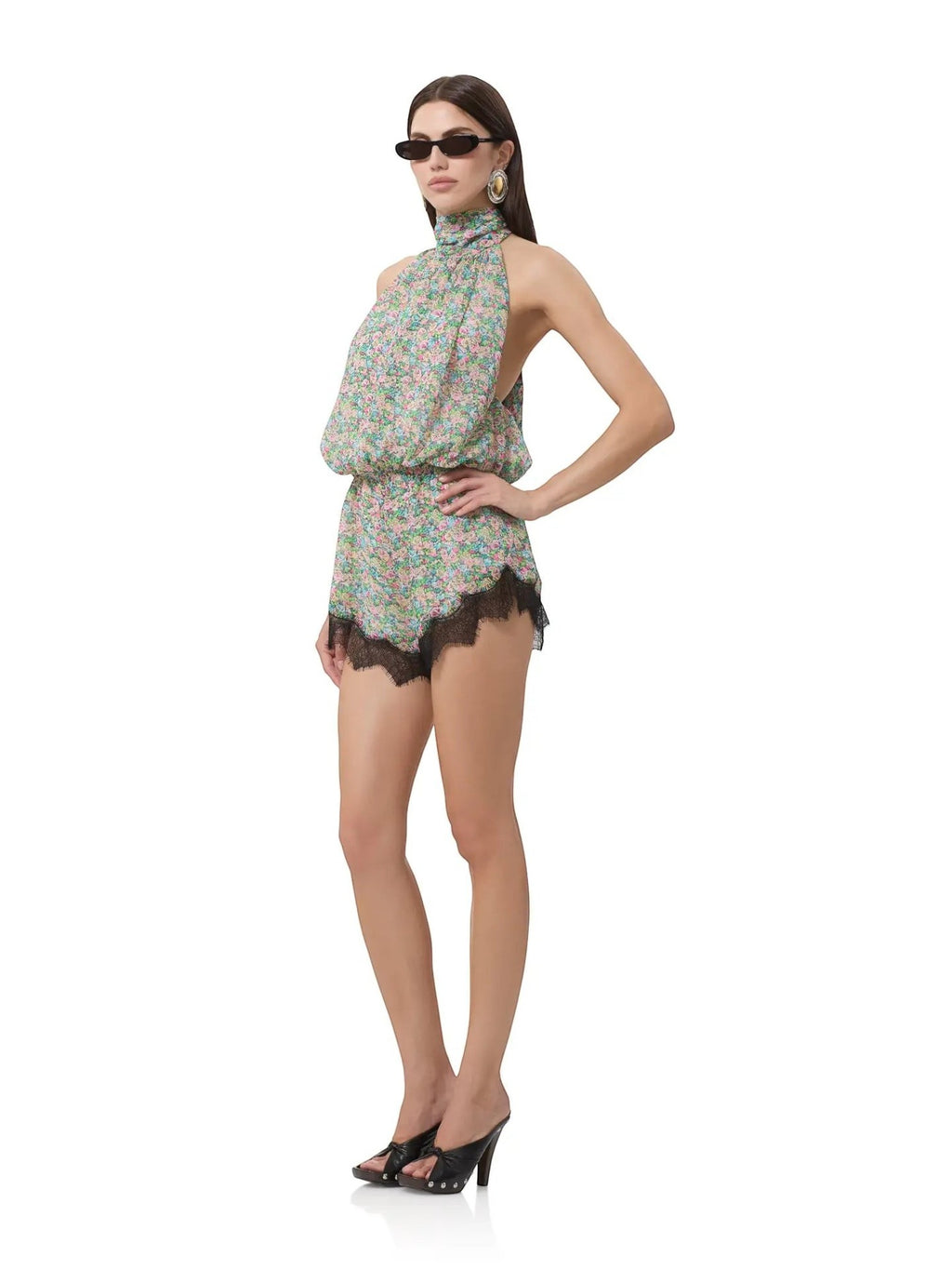 Model wearing Mialur Fleur floral romper with high neckline and black lace hem, styled with sunglasses and heels.