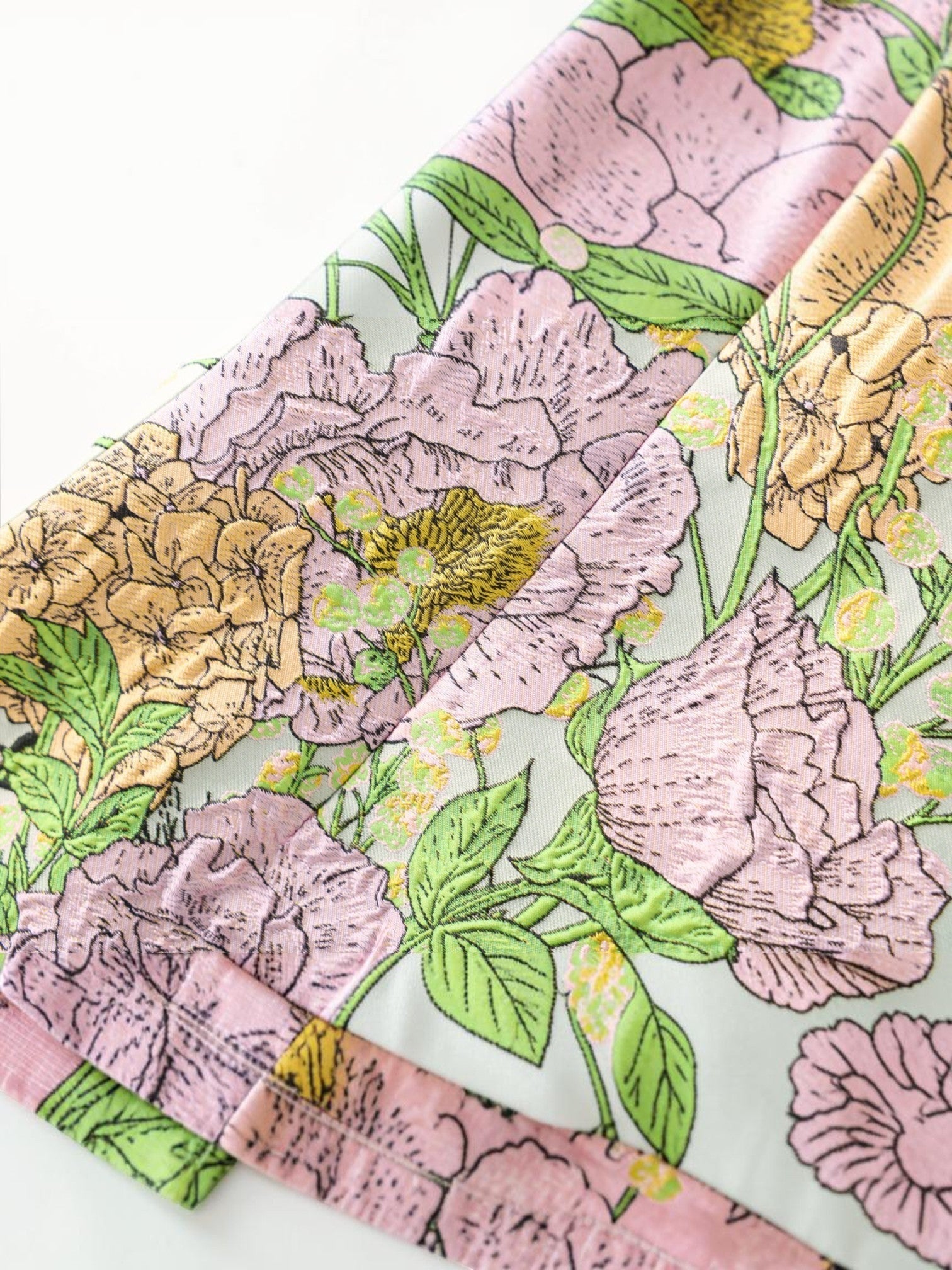 Close-up of Mialur Flora Mini Dress fabric featuring sage green base with lavender and golden floral botanical print.