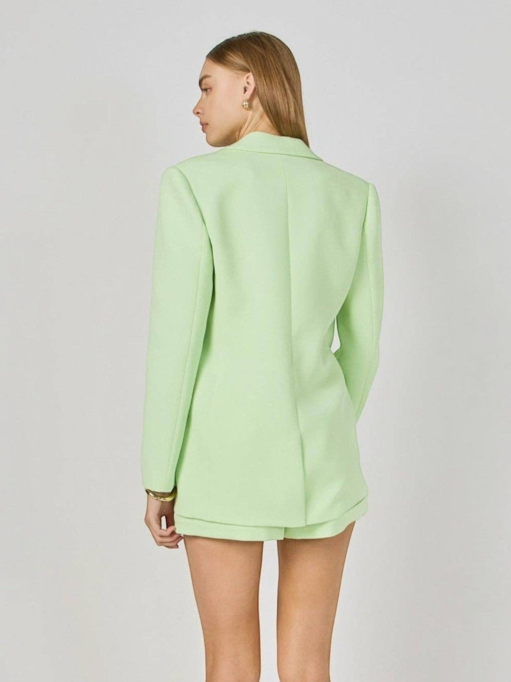 Back view of a model wearing a Mialur Florida Blazer in sugar lime green with a relaxed oversized fit.