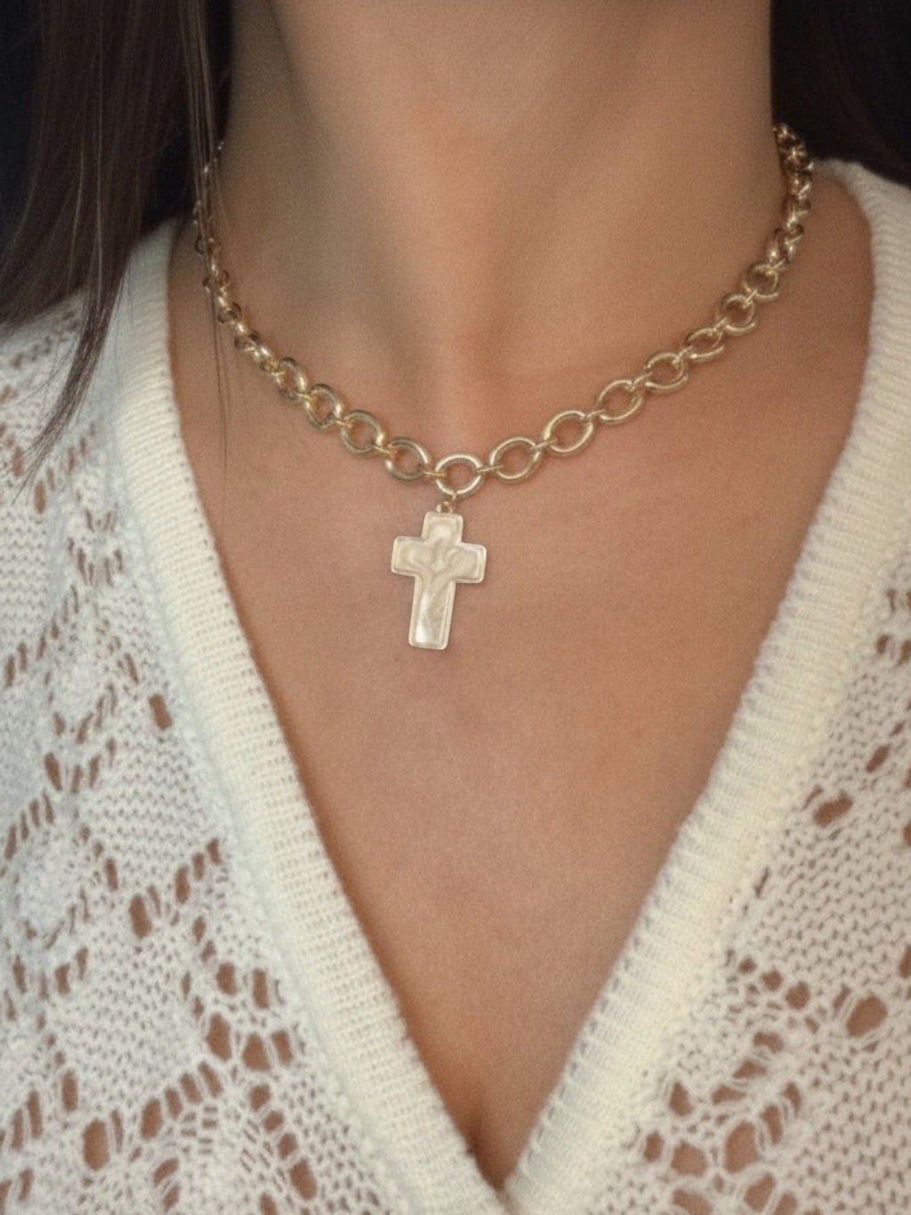 Mialur gold cross charm necklace with a delicate linked chain worn on a person in a white knit top