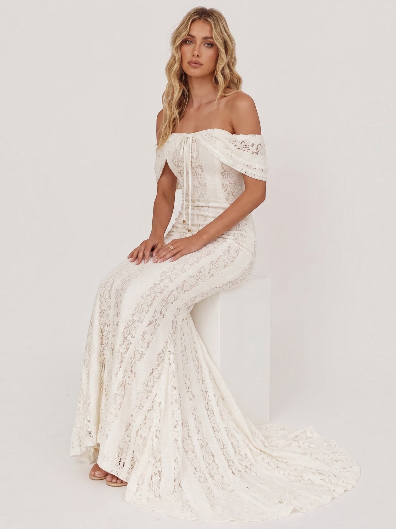 Model wearing a Mialur ivory off-the-shoulder lace maxi dress with a fitted bodice and flared skirt on a white background