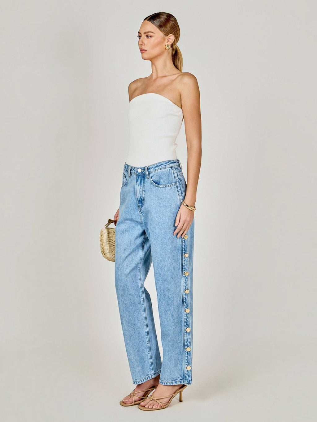 Model wearing Mialur light-wash blue straight-leg jeans with statement side button detail and mid-rise waist