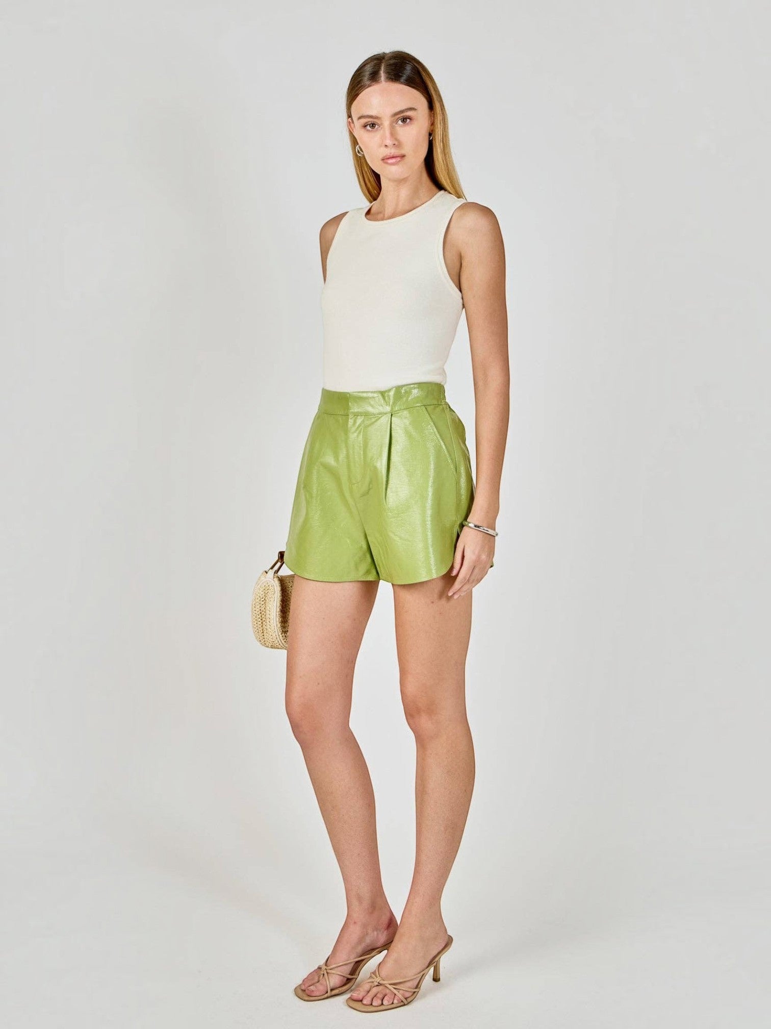 Model wearing Mialur lime green high-waisted faux leather tailored shorts with front pleats and side pockets.
