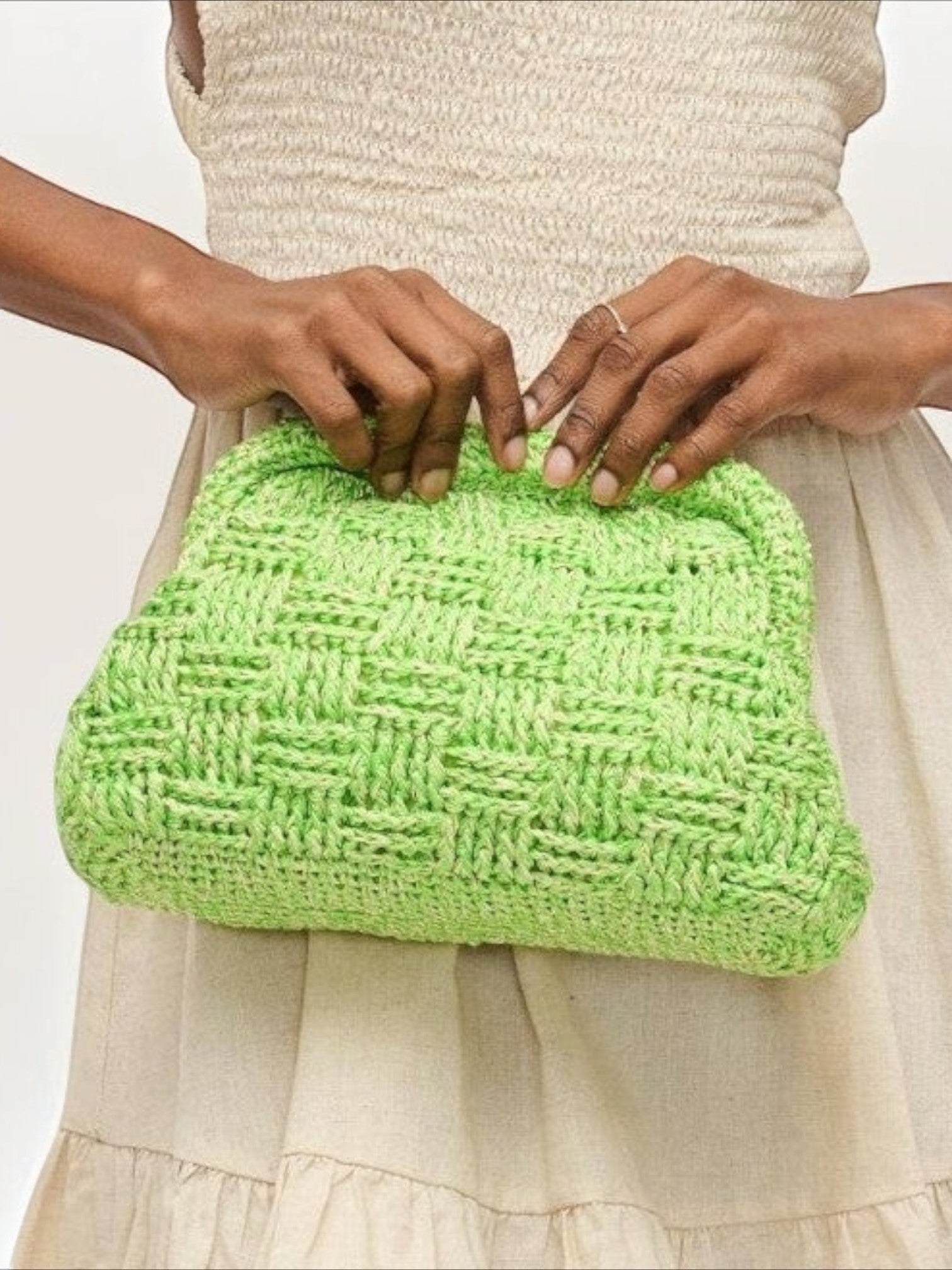 Mialur lime green woven clutch bag with a textured finish held by a person wearing a neutral summer dress.