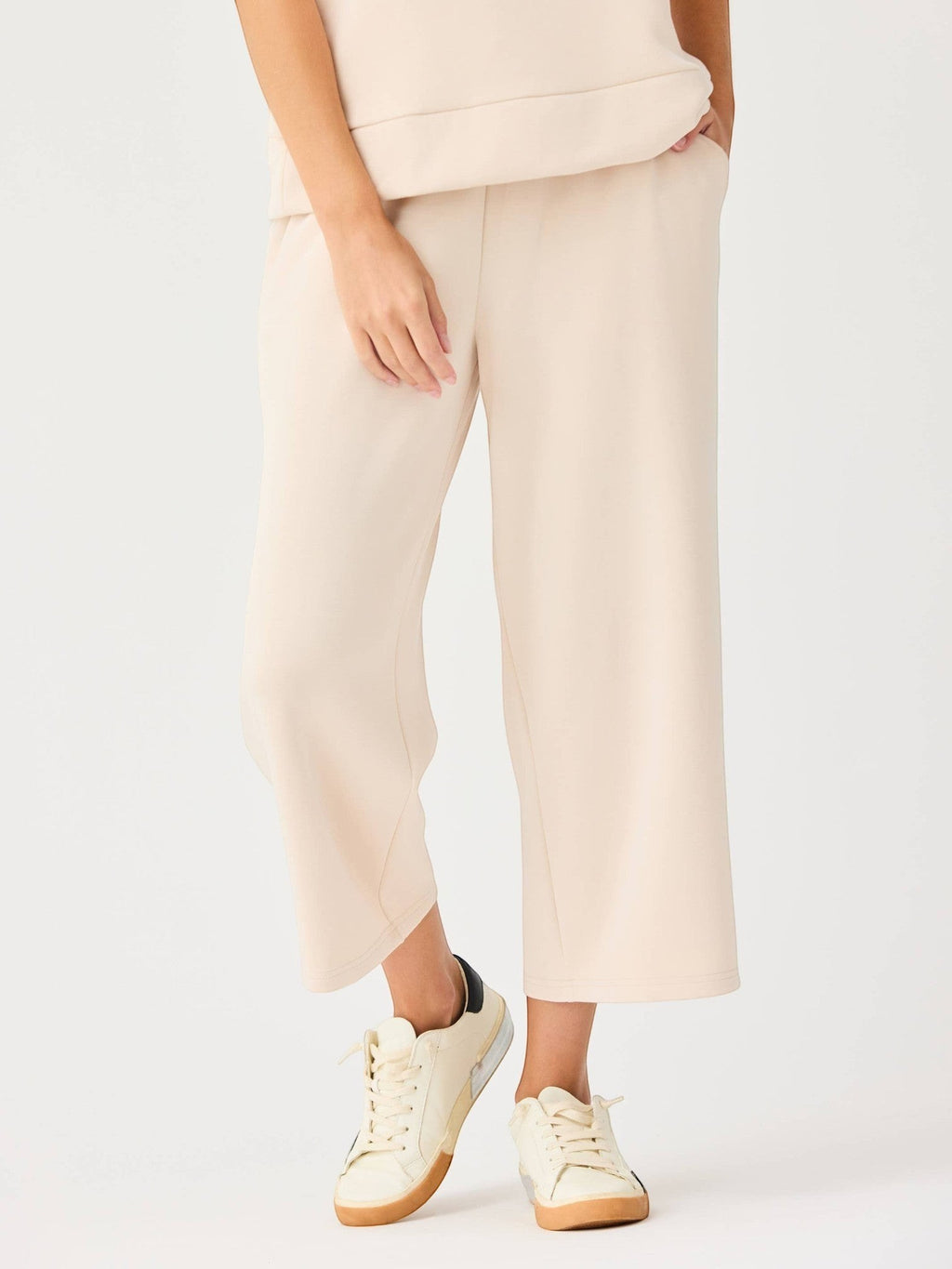 Mialur Marina Pants in sand featuring a relaxed wide-leg silhouette and elastic waistband worn with casual sneakers.