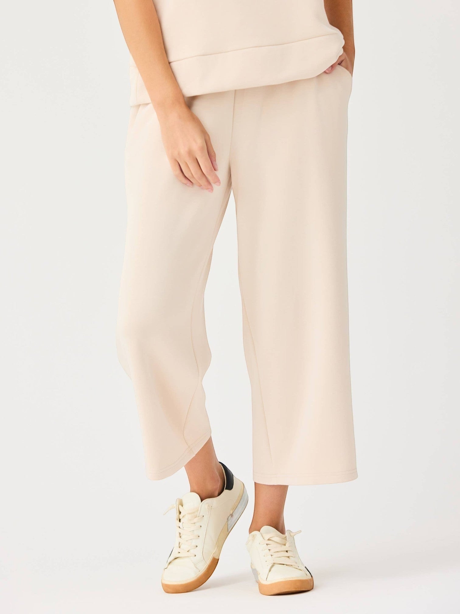 Mialur Marina Pants in sand featuring a relaxed wide-leg silhouette and elastic waistband worn with casual sneakers.