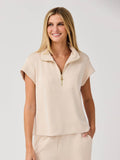 Mialur Marina Polo in sand featuring a relaxed fit, collared neckline, and a gold half-zip detail on a model.