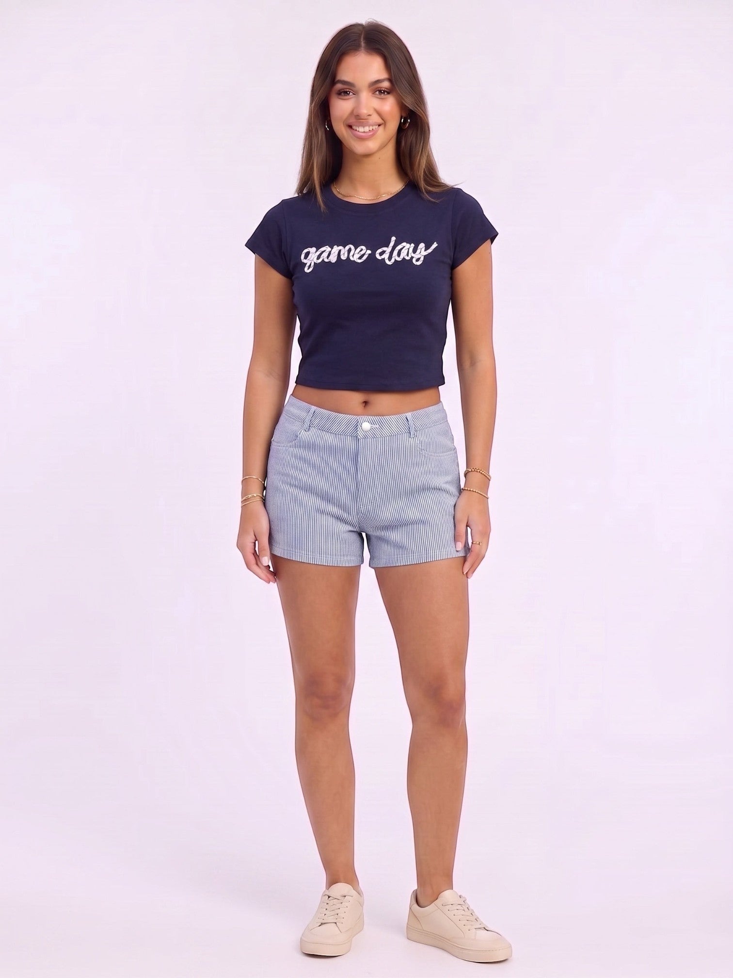 Mialur navy fitted baby tee with white game day script worn by a model with striped shorts and sneakers