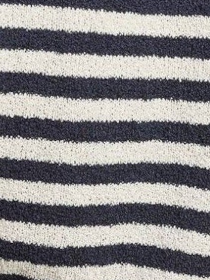 A close-up of a textured knit fabric with horizontal stripes in dark navy blue and off-white.