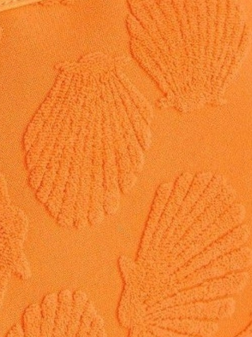 Close-up of an orange textured surface with embossed scallop or shell-like patterns.