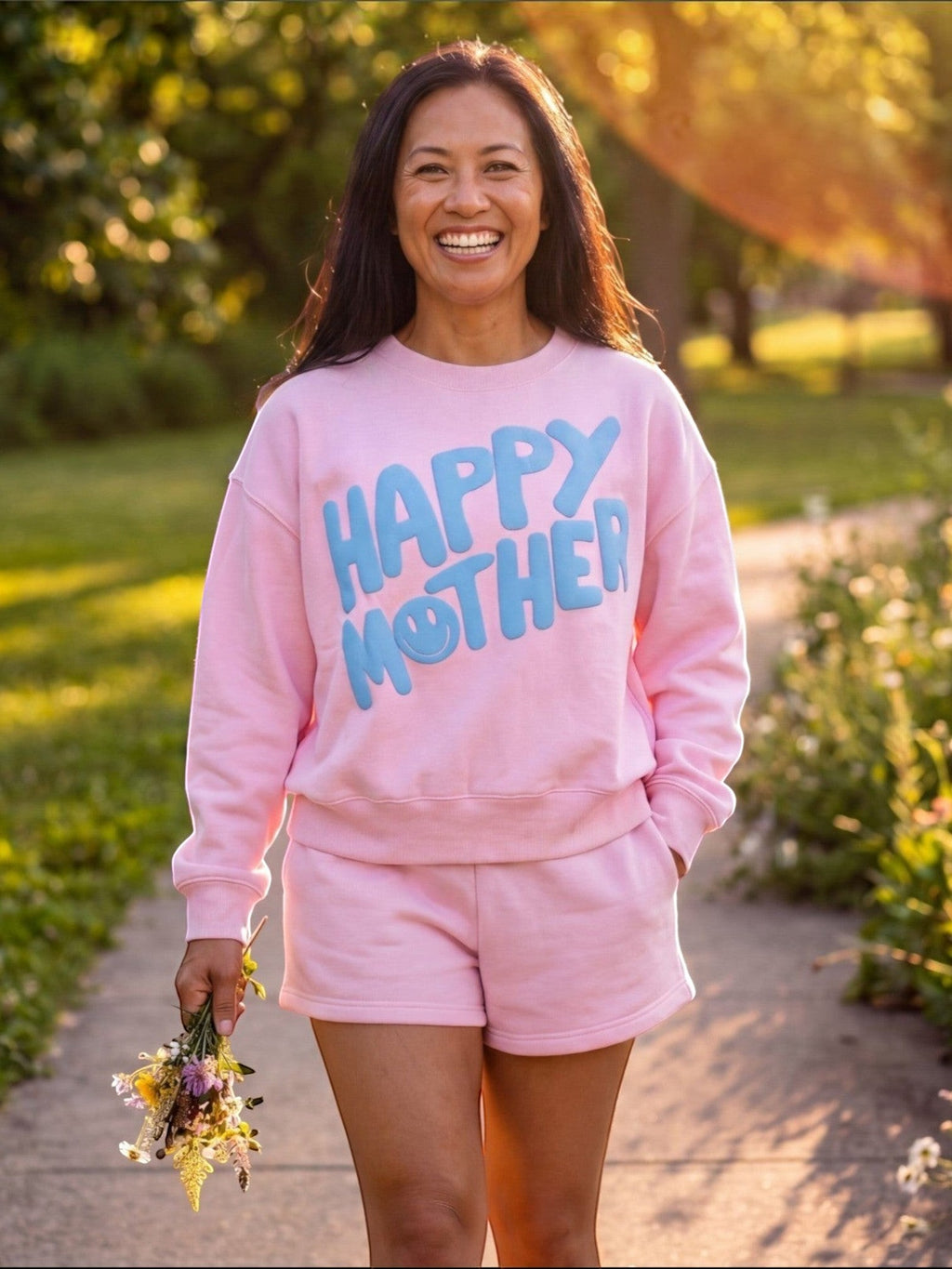 Mialur pink Happy Mom sweatshirt with blue HAPPY MOTHER graphic worn by a smiling woman outdoors at sunset